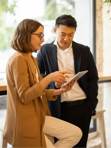 Two colleagues reviewing content together on a tablet