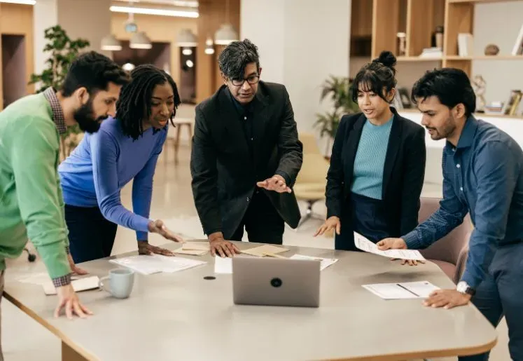 Team collaborating and brainstorming around a table with a laptop
